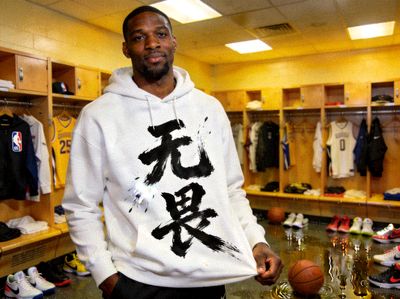 NBA球员卫衣上印有巨大的汉字书法‘无畏’二字，笔触苍劲有力，背景是更衣室